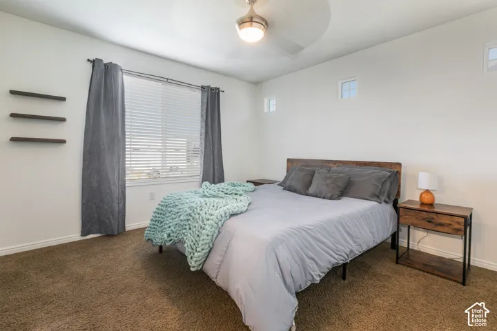 Room featuring neutral carpeted flooring, built-in floating shelves, two high-set accent windows, and a central brushed-nickel ceiling fan with integrated light