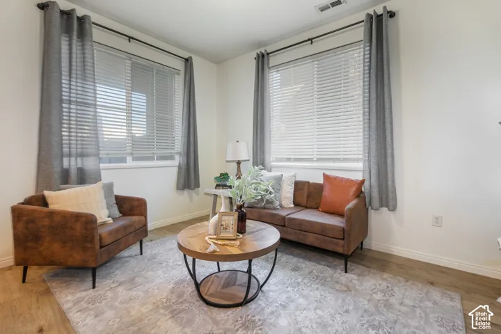 Bright interior room featuring wood-finish flooring, neutral wall paint, and dual windows with horizontal blinds