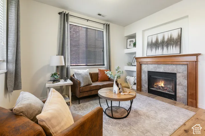 Fireplace featuring a stone-tile surround, wood mantle, and built-in recessed shelving on wood-finish flooring