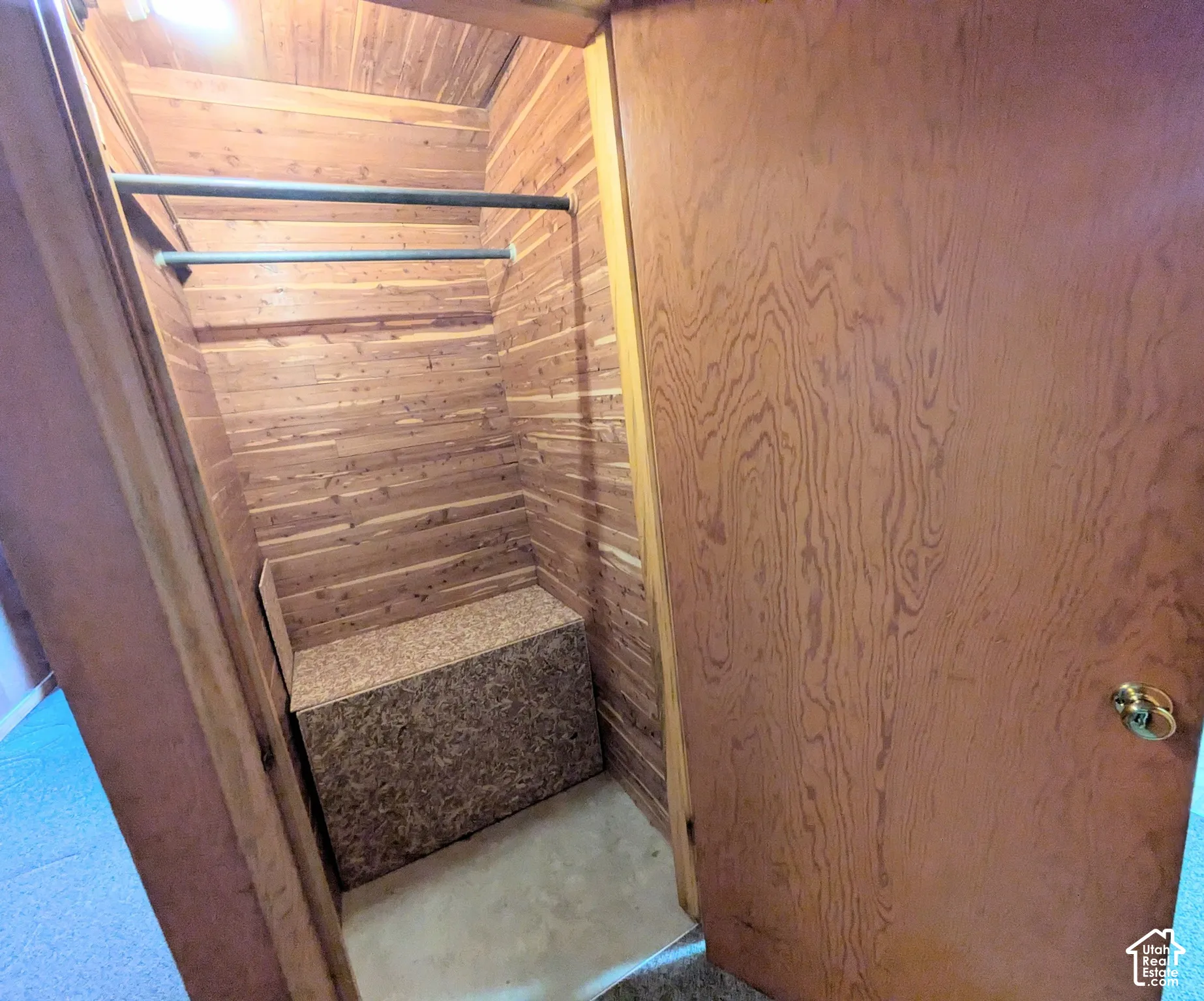 Storage space featuring cedar wood wall paneling, dual metal hanging rods, and a built-in cabinetry unit