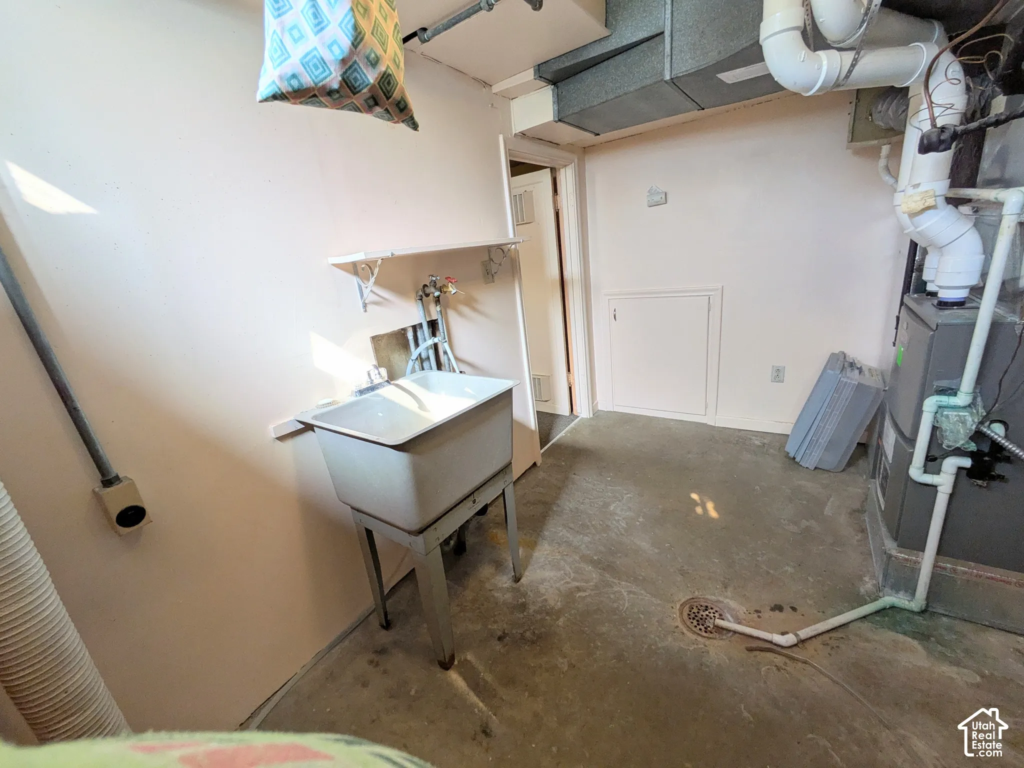 Utility area featuring a floor-mounted basin, concrete flooring, and mechanical systems