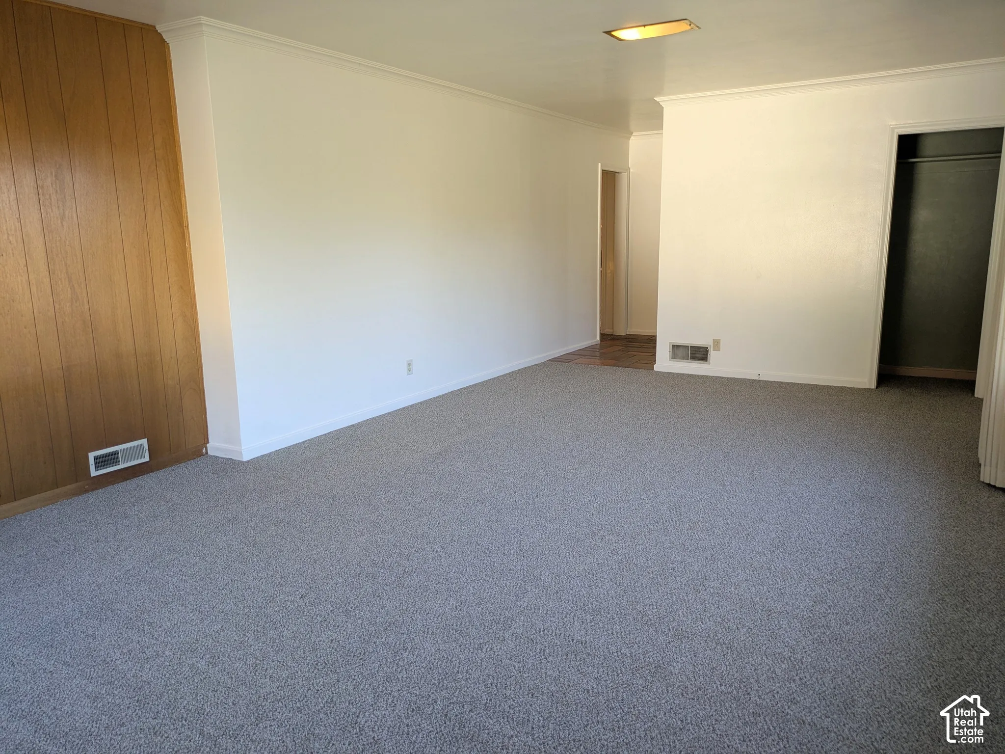 Neutral-toned carpeting, wood-paneled accent wall, and recessed ceiling lighting