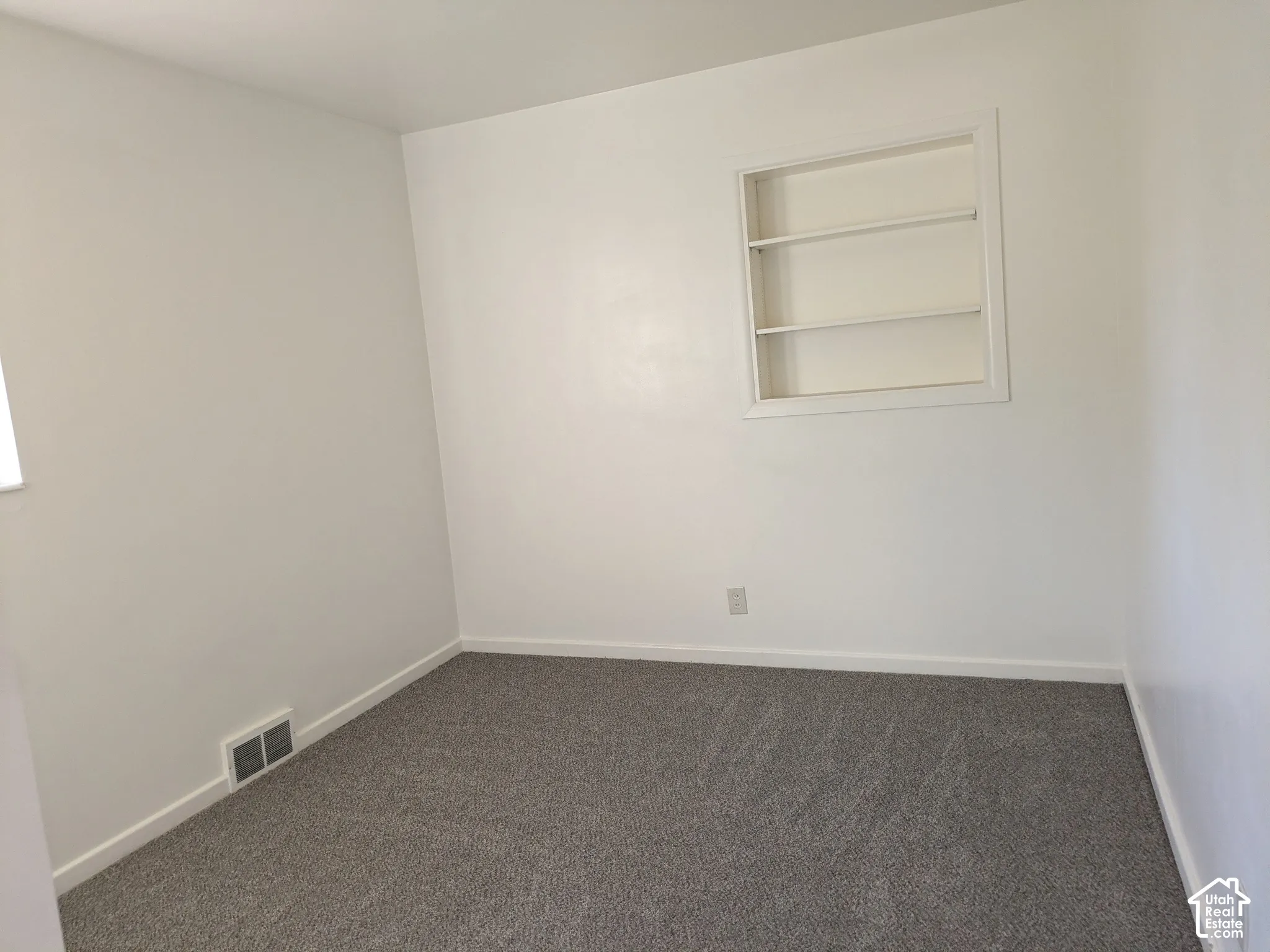 Interior space featuring neutral wall tones, wall-to-wall carpeting, and a built-in recessed shelving unit