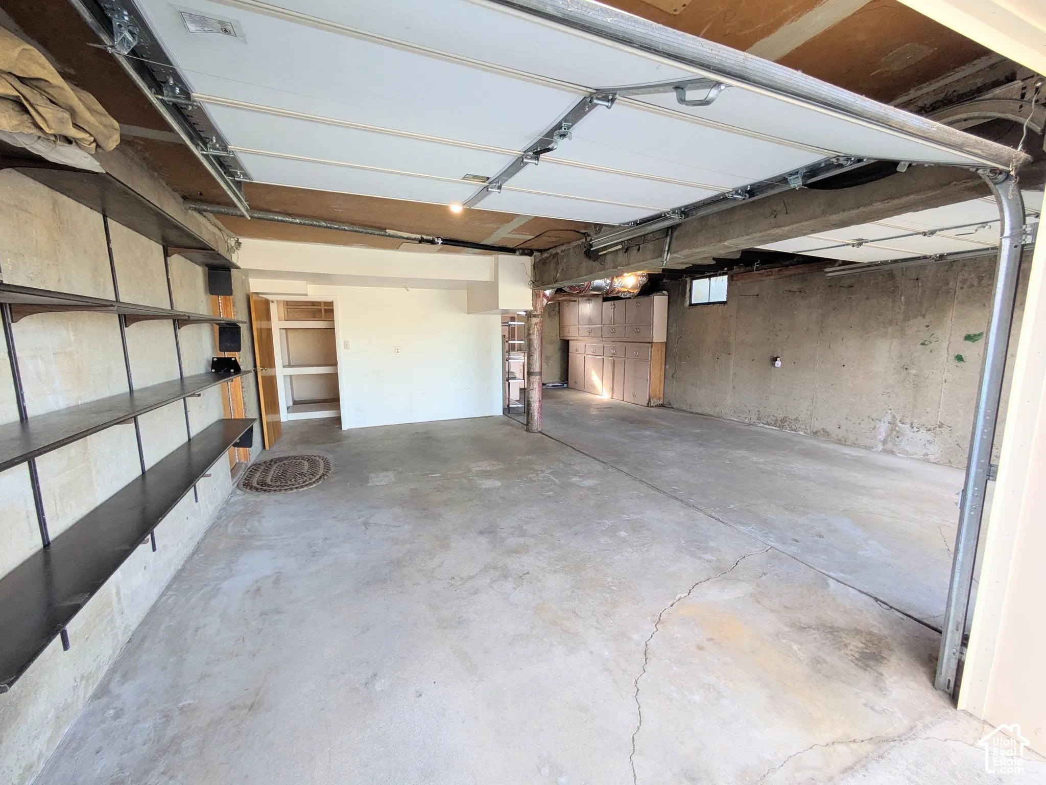 Attached garage featuring concrete flooring, wall-mounted metal shelving, and built-in wooden storage cabinetry