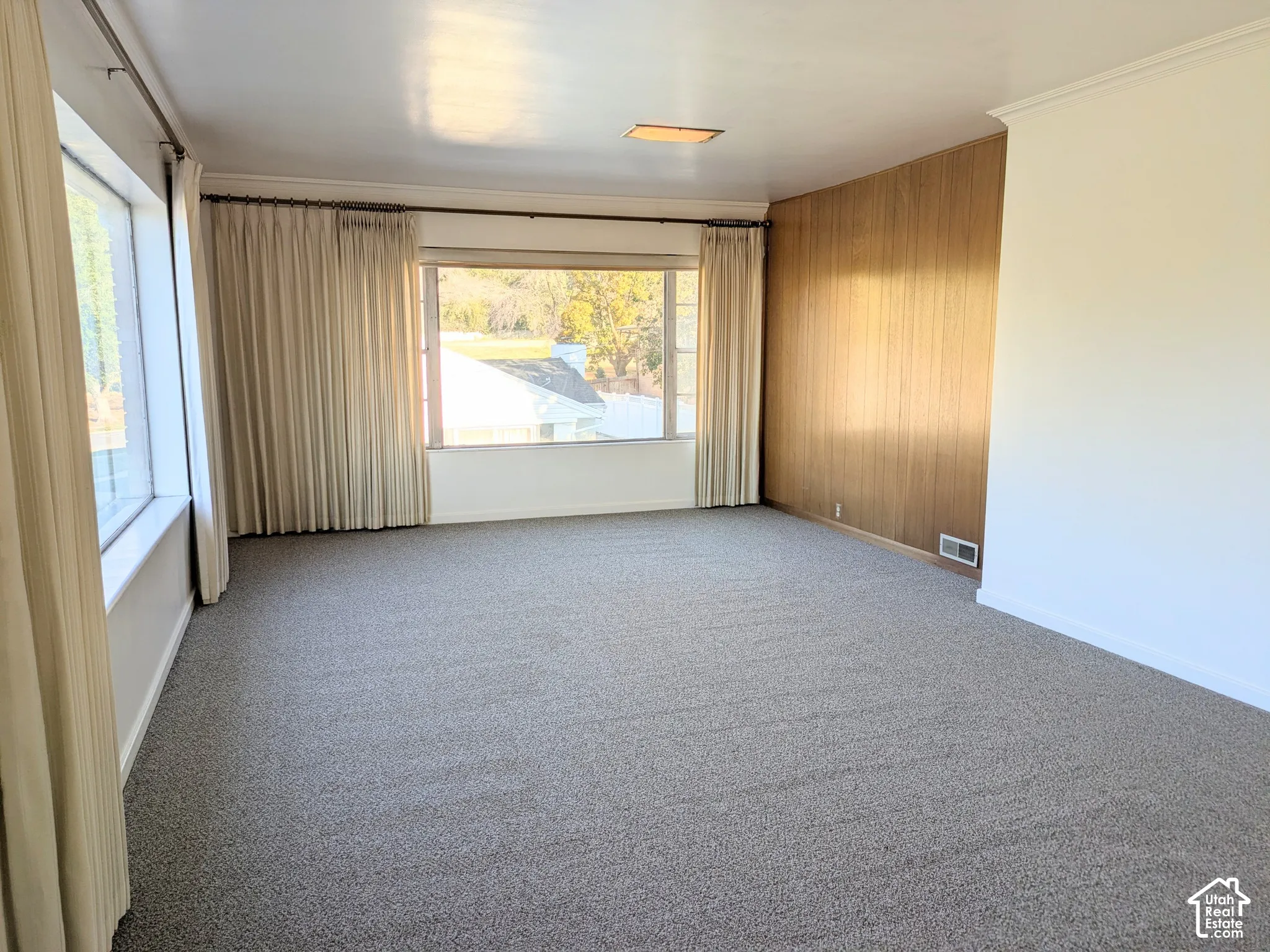 Interior space featuring expansive picture windows, wood-panel accent wall, neutral carpeting, and recessed ceiling lighting