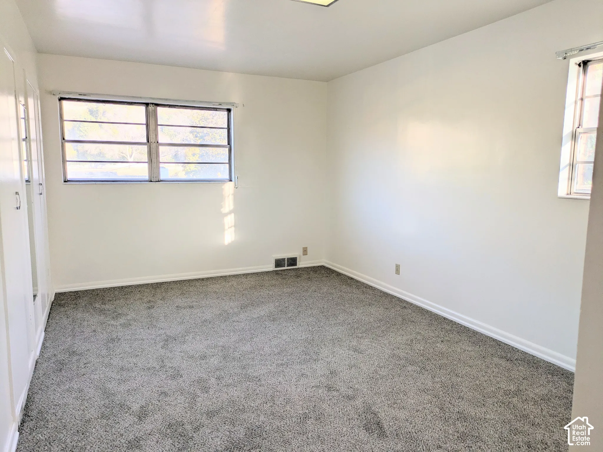 Neutral-toned carpeted flooring, built-in floor-to-ceiling closets, and multi-pane windows with horizontal muntins