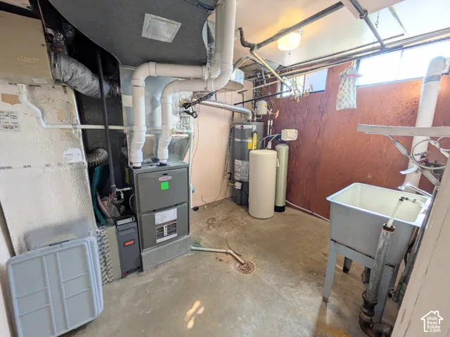 Utility area featuring a Lennox gas furnace, water heater, water softening system, and utility sink with concrete flooring