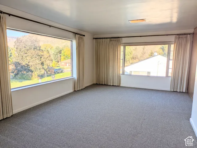 Spacious room featuring neutral carpeting, expansive picture windows, and mountainous scenery