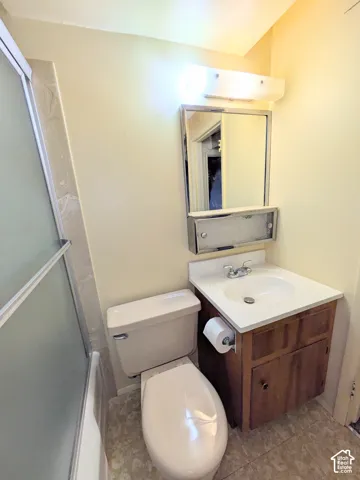 Full bathroom featuring a shower stall with frosted glass doors, wooden vanity cabinet, integrated sink with chrome faucet, and a wall-mounted medicine cabinet with mirror