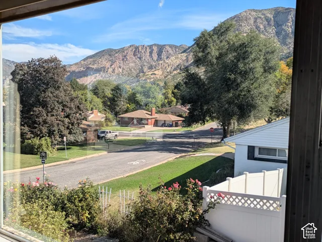 Prominent mountain backdrop featuring mature trees, white vinyl privacy fencing, and residential landscaping