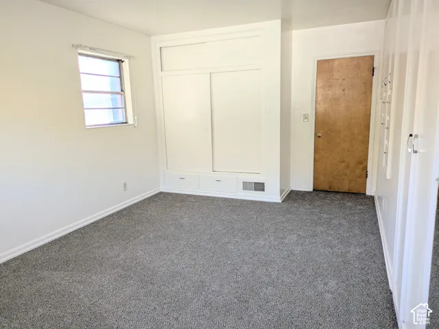 Neutral-toned carpet, built-in storage cabinetry with sliding doors and integrated drawers, and a single-pane window with grid inserts