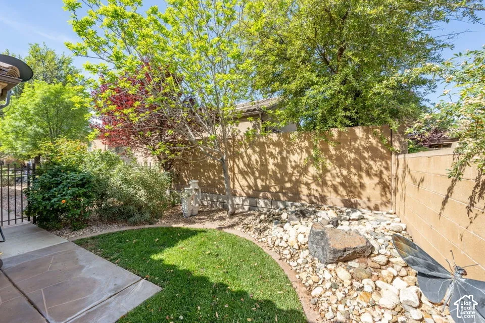 Backyard featuring a paved patio, a grass lawn, decorative stone ground cover, and a masonry perimeter wall