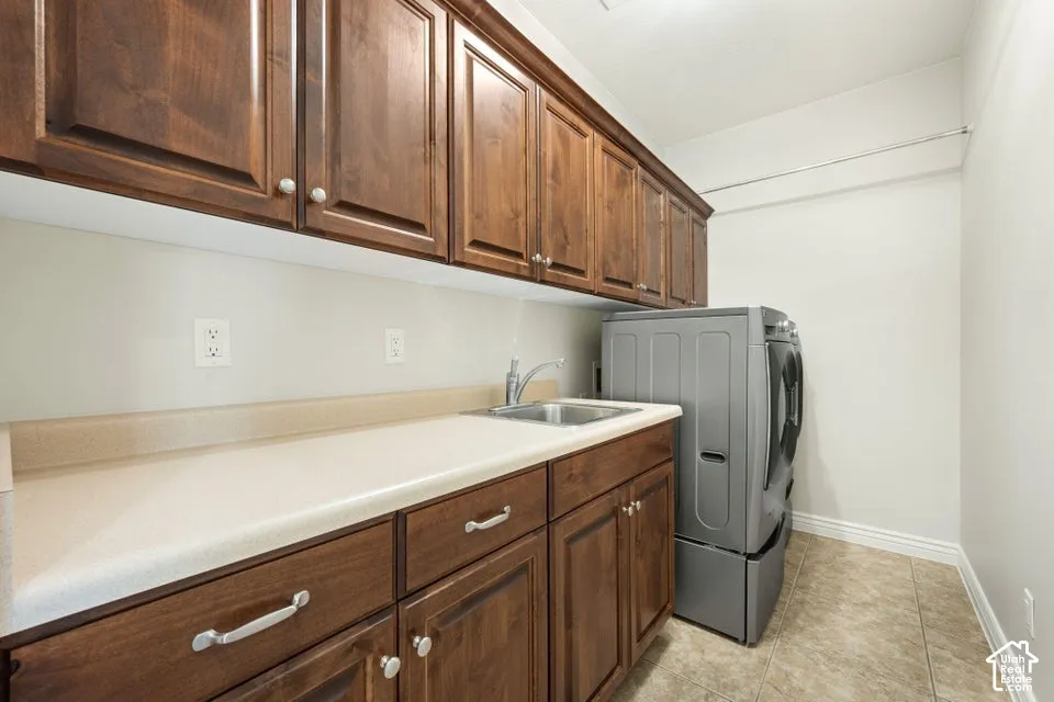 Upper and lower cabinetry with wood-finish doors, solid-surface countertop, stainless steel drop-in sink with arched faucet, and tile flooring