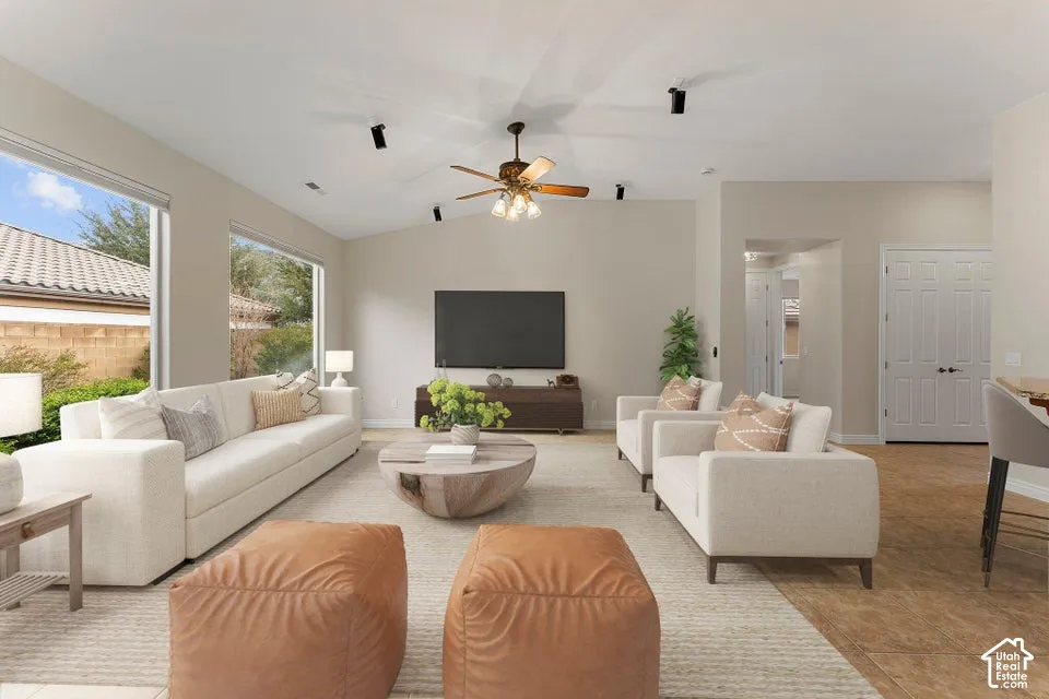 Living area featuring vaulted ceilings, recessed track lighting, large windows, a ceiling fan with integrated light fixture, and tile flooring