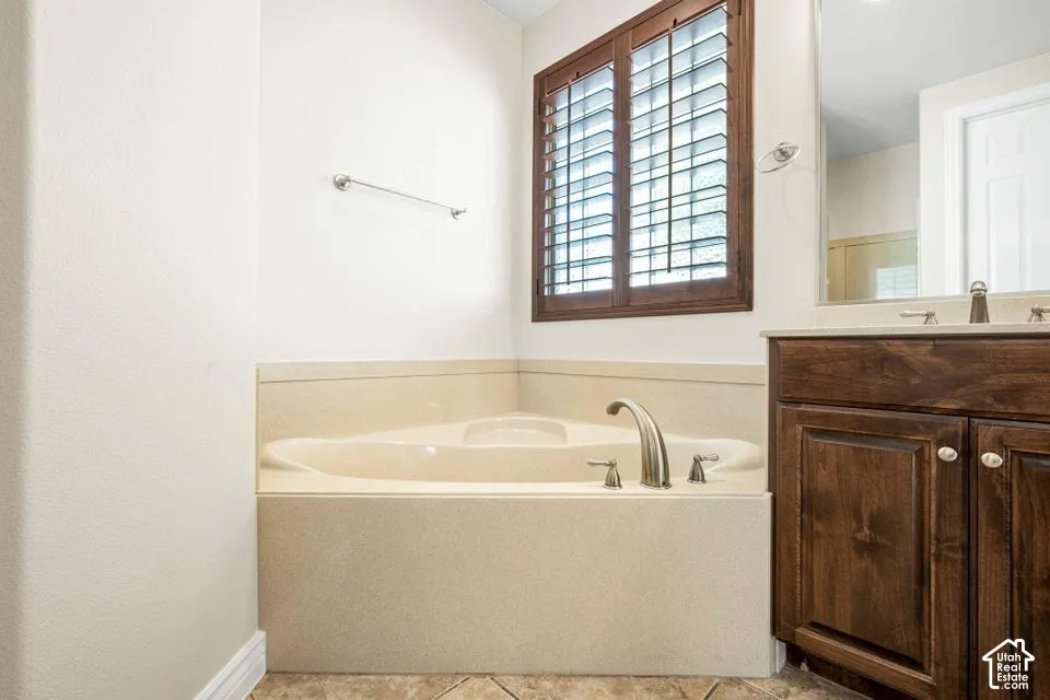 Corner soaking tub with integrated surround, dark wood-finish cabinetry, neutral countertop, and dark-finished window shutters