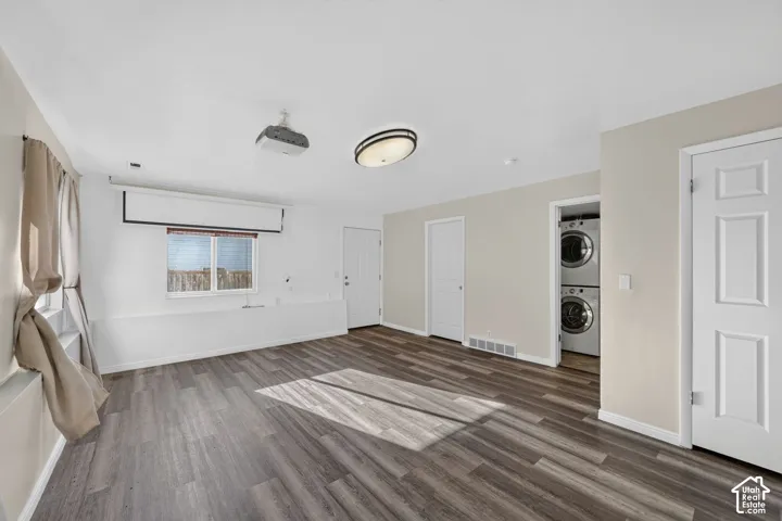 Room featuring wood-finish flooring, recessed projector, retractable projection screen, and built-in stacked laundry units