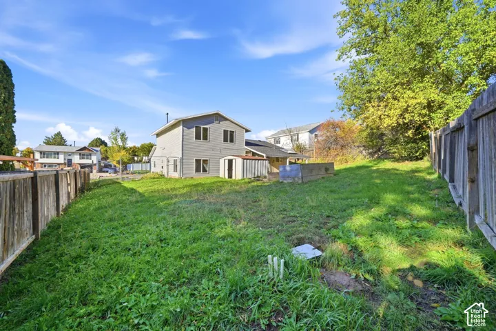 Expansive backyard featuring wood perimeter fencing, mature trees, and a detached metal storage structure
