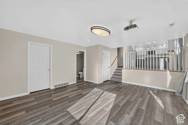 Wood-finish flooring, neutral wall tones, ceiling-mounted projector, and white balustrade railing