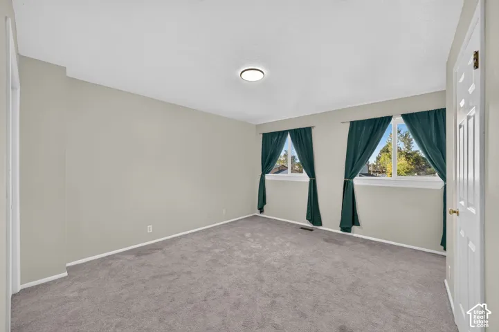 Neutral-toned interior space featuring carpeted flooring, two double-pane windows, and a flush-mount ceiling light fixture