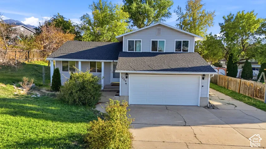 Split-level exterior featuring horizontal siding, a multi-gabled asphalt shingle roof, a two-car garage, and mountain scenery