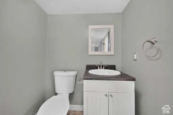 White vanity with beadboard cabinet doors, dark countertop, undermount sink, brushed nickel faucet, and wall-mounted towel ring