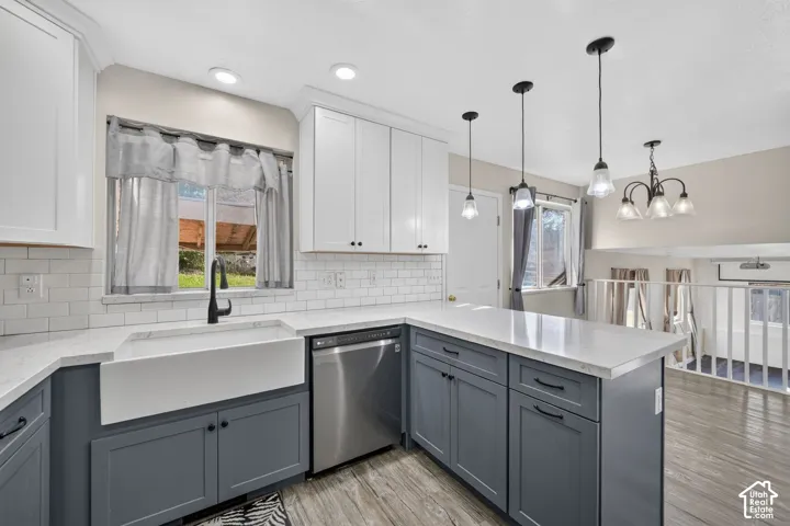 Kitchen featuring two-tone shaker cabinetry, quartz countertops, white subway tile backsplash, apron-front farmhouse sink with matte black faucet, and stainless steel dishwasher