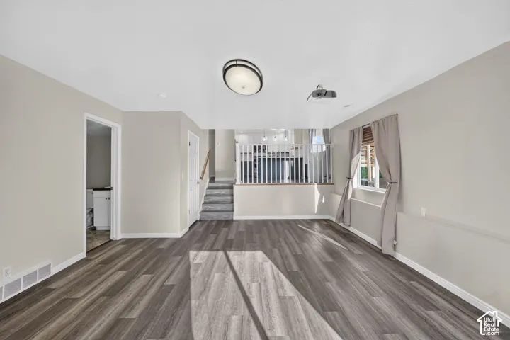 Living area featuring wood-finish flooring, ceiling-mounted projector, neutral paint palette, and white spindle railing