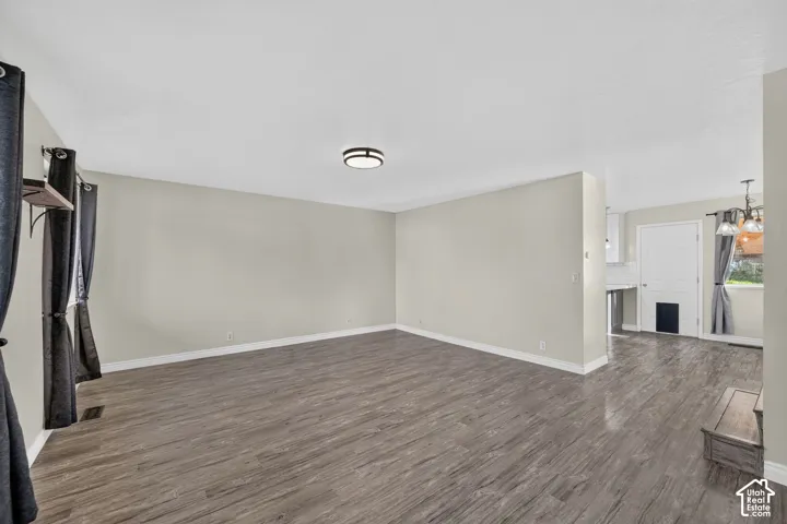 Interior space featuring wood-finish flooring, neutral wall paint, and a central flush-mount ceiling light fixture