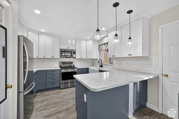 Kitchen featuring two-tone cabinetry, stone-finish countertops, subway tile backsplash, farmhouse sink, and three glass pendant lights