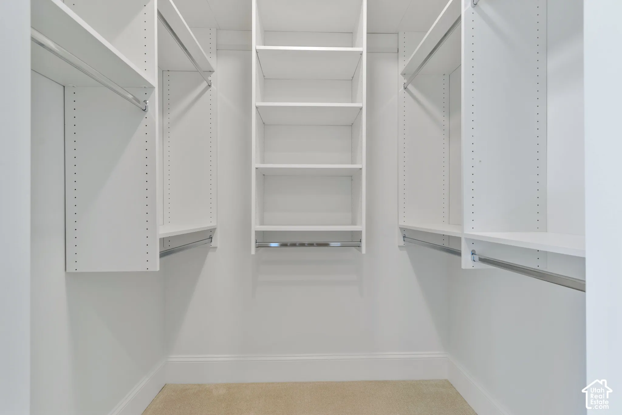 Walk-in closet featuring white built-in shelving, adjustable shelving units, and integrated metal clothing rods
