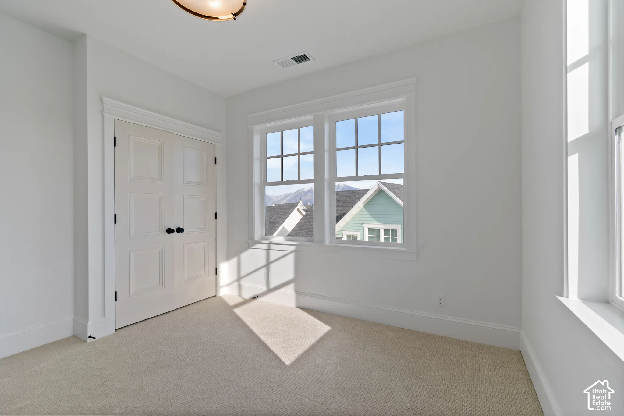 Double French doors with matte black hardware, multi-pane windows with detailed casing, carpeted flooring, and mountain backdrop