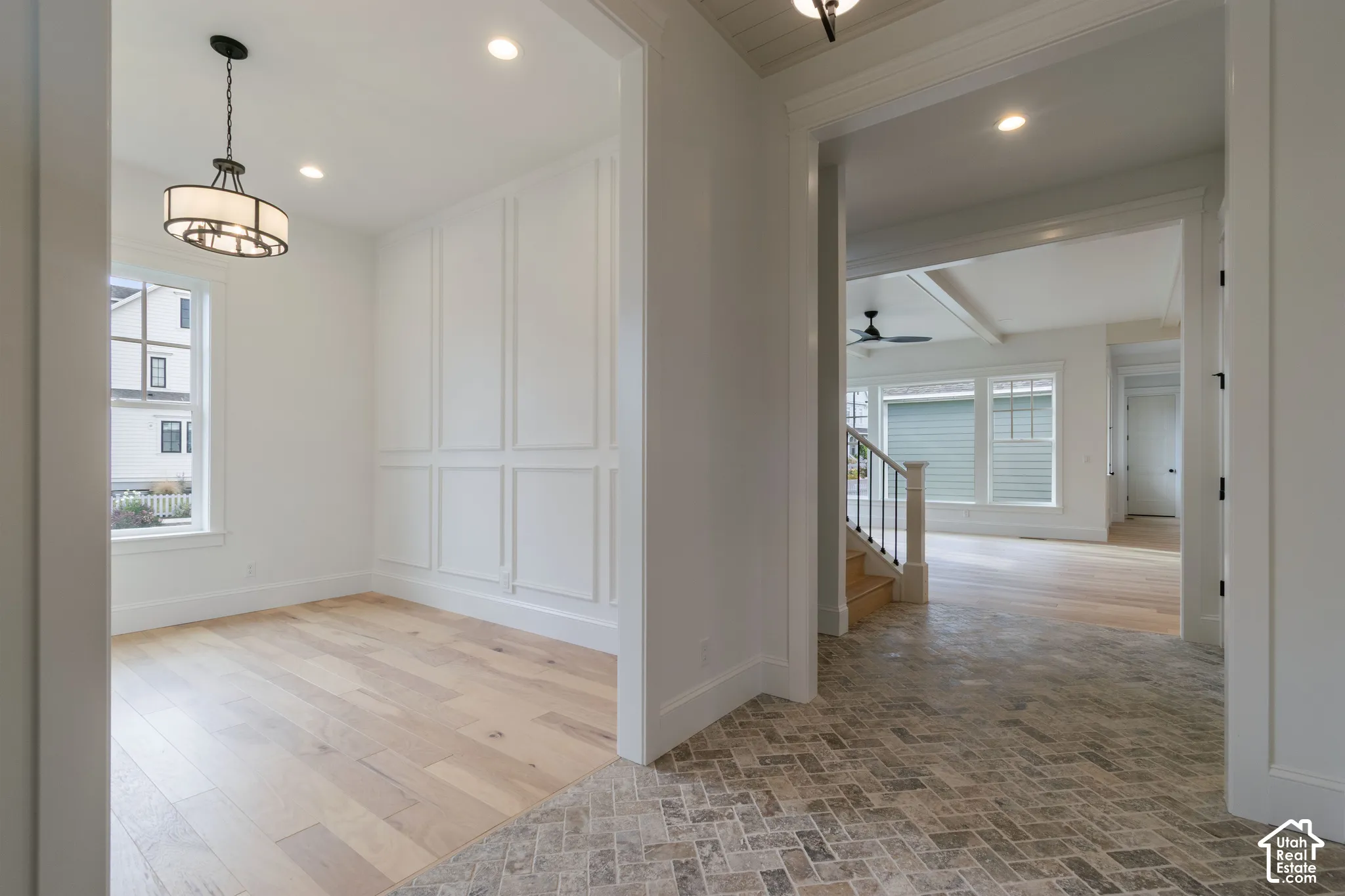 Foyer featuring herringbone-patterned stone flooring, wood-finish flooring, wainscoting, recessed lighting, and a drum-style pendant fixture