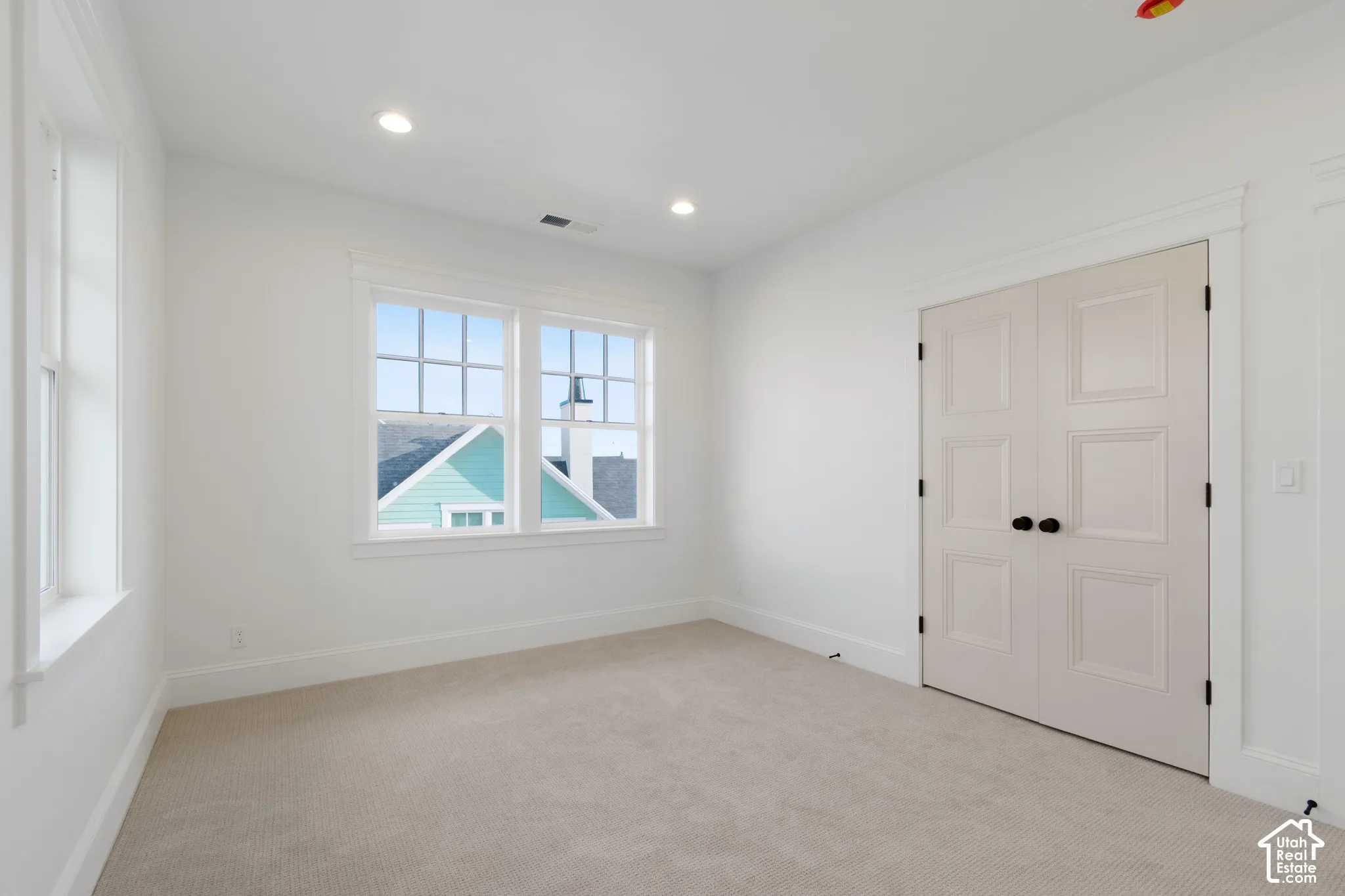Interior room featuring neutral carpeting, recessed ceiling lighting, multi-pane windows with casing, and double doors with matte black hardware