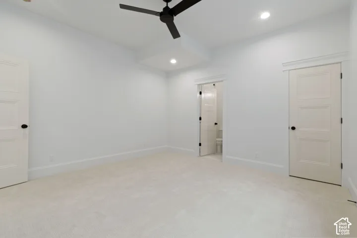 Room featuring a recessed ceiling detail, matte black ceiling fan, recessed lighting, wall-to-wall carpeting, and solid-core doors with matte black hardware