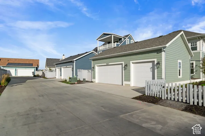 Detached two-car garage with lap siding, concrete driveway, and white picket fencing