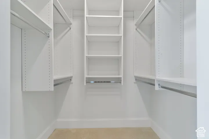 Walk-in closet featuring white built-in shelving, adjustable shelving units, and integrated metal clothing rods