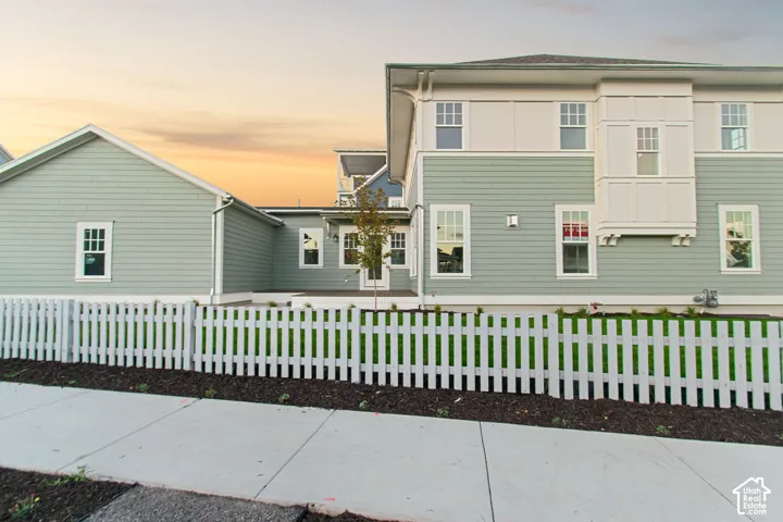 Exterior featuring light green horizontal siding, white trim accents, a prominent bay window, and a white picket fence enclosing a lawn area