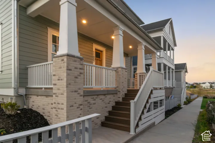 Covered front porch featuring tapered columns, brick masonry base, horizontal lap siding, and white railing