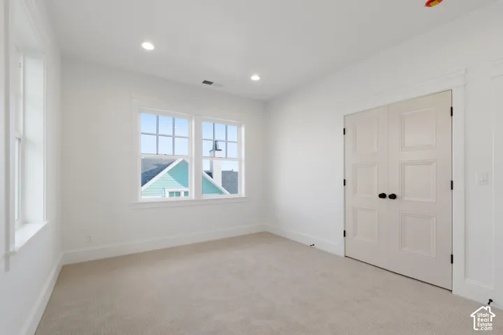 Interior room featuring neutral carpeting, recessed ceiling lighting, multi-pane windows with casing, and double doors with matte black hardware