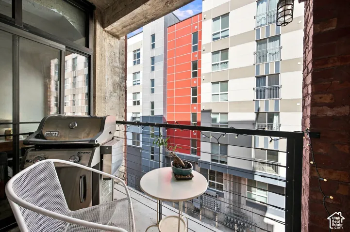 Private balcony with cable railing, concrete ceiling, and exposed brick wall