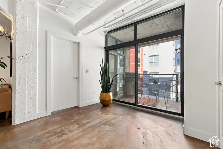 Exposed concrete flooring, full-height glass patio doors, and exposed ceiling ductwork