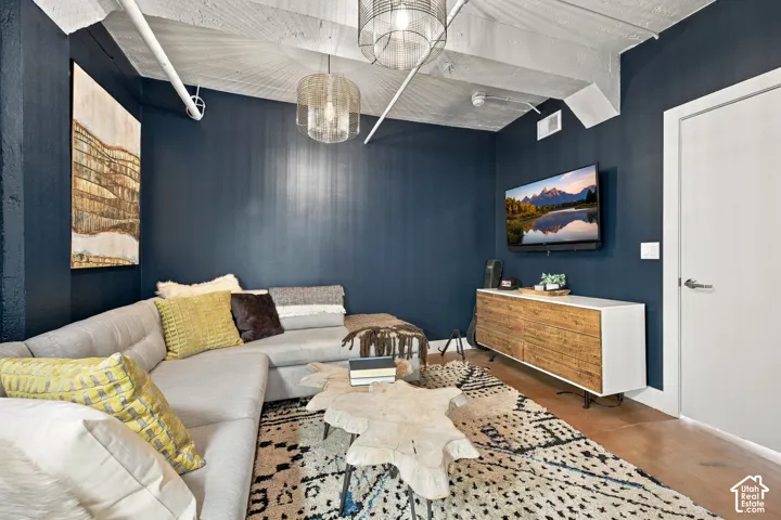 Exposed ceiling beams, dark accent wall, wood-finish flooring, built-in media console, and recessed lighting