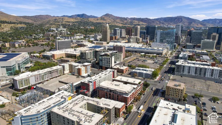 Expansive urban landscape featuring diverse architectural styles, visible roadways, and distant mountain ranges