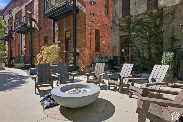 Paved patio area featuring a concrete fire pit, string lighting, and direct access to brick and stucco structures with multiple balconies