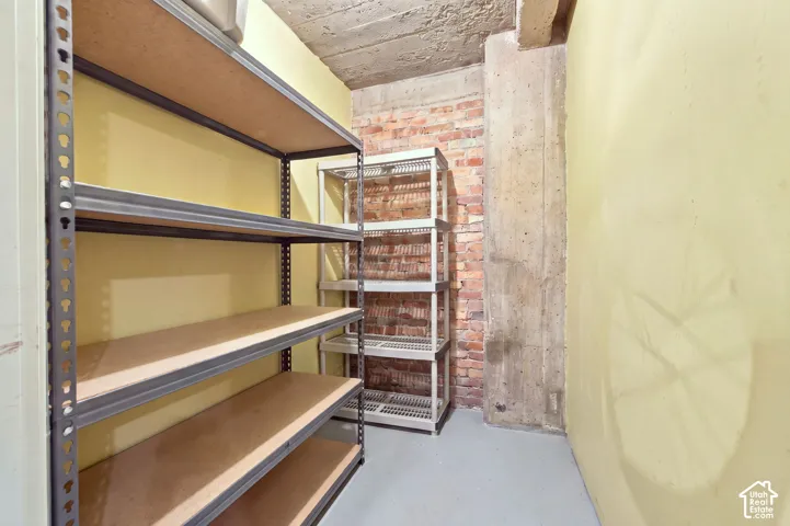 Exposed brick wall, concrete support beams, concrete ceiling, light yellow painted walls, and light gray flooring