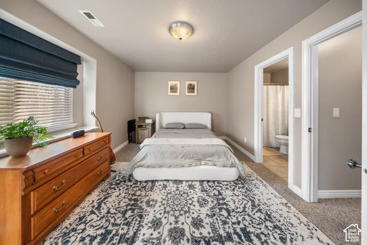Neutral-toned bedroom featuring carpeting, ceiling-mounted light fixture, recessed window sill, and a multi-panel door leading to a secondary room