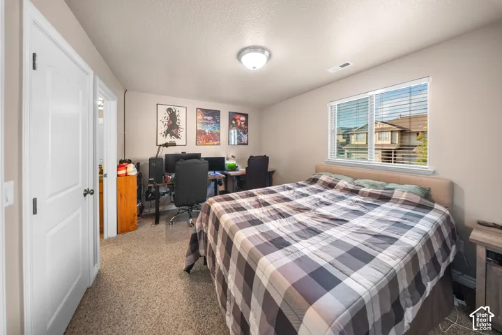 Neutral-toned bedroom featuring plush wall-to-wall carpeting, a multi-pane window with adjustable horizontal blinds, and a solid-core interior door