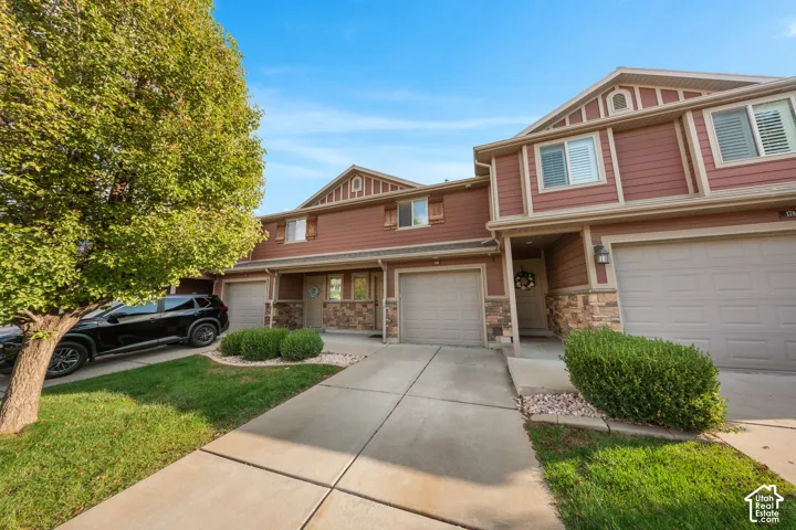 Multi-level exterior featuring horizontal siding, decorative stone veneer, gabled rooflines, two attached garages, and a concrete driveway