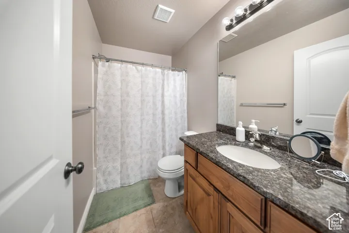 Bathroom featuring a vanity with dark stone-finish countertop, an integrated oval basin, a full-width mirror, and a shower-tub combination with chrome fixtures