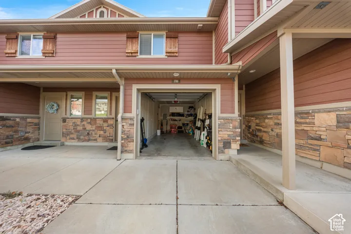 Exterior featuring horizontal lap siding, stone veneer masonry, wood-accented window shutters, and a concrete driveway leading to an attached garage